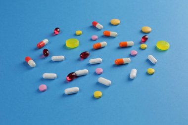 Mavi arka planda çeşitli şekillerde çok renkli haplar. Yakın plan.