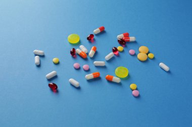 Mavi arka planda çeşitli şekillerde çok renkli haplar. Yakın plan.