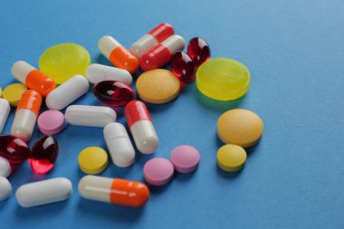 Mavi arka planda çeşitli şekillerde çok renkli haplar. Yakın plan.