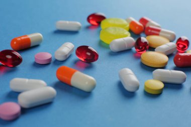 Mavi arka planda çeşitli şekillerde çok renkli haplar. Yakın plan.