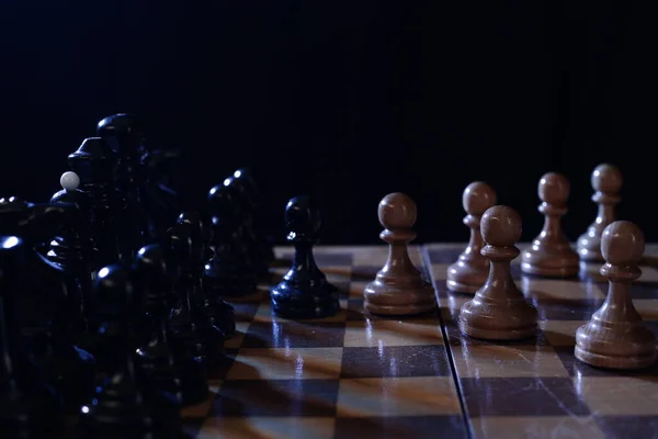 Tahta satranç bir masa oyunudur. Karanlık bir arkaplanda satranç taşları