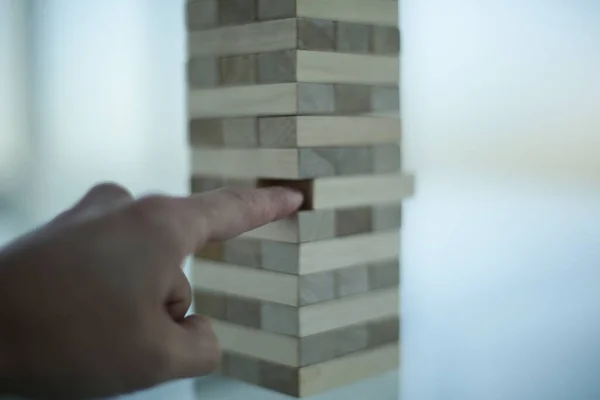 Hand, board game - wooden bars on a glass table in office