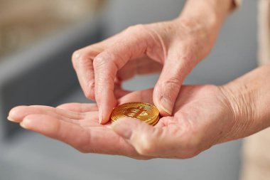 Yaşlı kadın elinde bitcoin para tutuyor. Yaşlı vatandaş mutlu yaşam konsepti