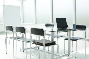 Flipchart dizüstü bilgisayar kahve fincanı telefon evrak çantası cam masa sandalyeleri ofis alanı