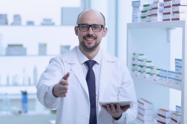 Eczacı çalışıyor. Eczanede özel sağlık üniforması giyen bir adam var..