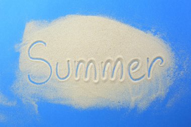 The word summer is written in the sand on a blue background. clipart
