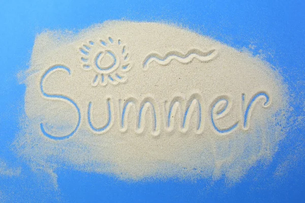 Das Wort Sommer und Symbol der Sonne steht in den Sand auf blauem Hintergrund geschrieben. — Stockfoto