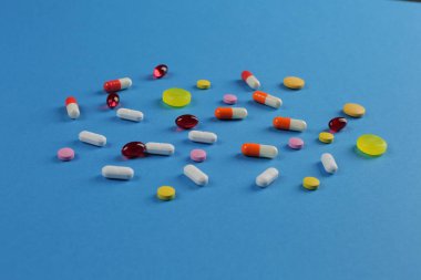 Mavi arka planda çeşitli şekillerde çok renkli tıbbi haplar.