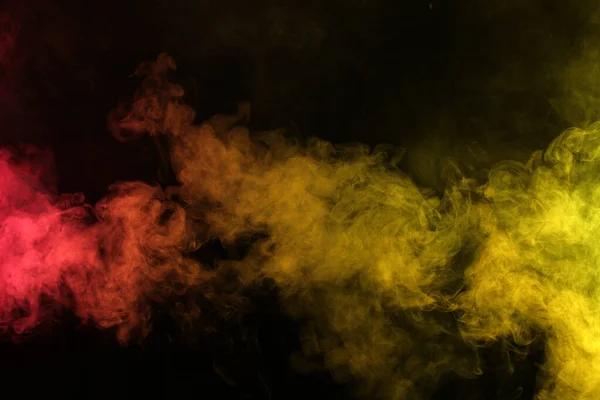 Savu puna-keltaisessa valossa mustalla taustalla pimeydessä — kuvapankkivalokuva