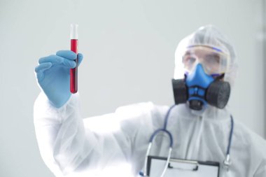 Koruyucu tıbbi giysili bir adam elinde bir test tüpü tutuyor. Coronavirüs 'e karşı açık aşı kavramı