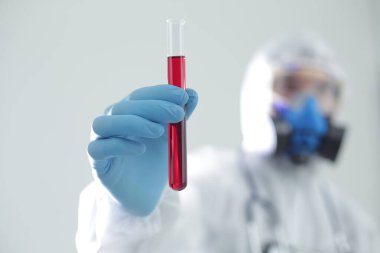 Koruyucu giysili bir adam elinde bir test tüpü tutuyor. Coronavirüs 'e karşı açık aşı kavramı