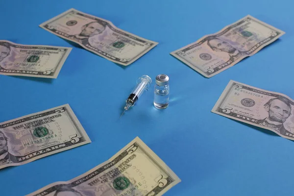 Syringe vial with vaccine and american dollars on blue background