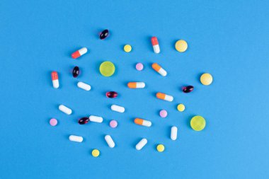 Mavi arka planda çeşitli şekillerde çok renkli haplar.