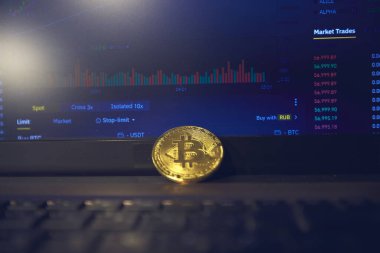 Laptop panelinde altın bir bitcoin var. Şifreleme kurlarını değiştirme sayfası dizüstü bilgisayarın ekranında açık.