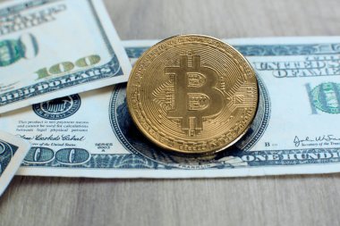 Bitcoin kripto para tahtadan bir masada 100 dolarlık banknotlar üzerinde yatıyor.