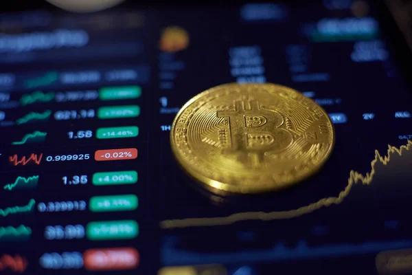Die Gold-Bitcoin-Münze liegt auf dem Tablet-Bildschirm, der zeigt, — Stockfoto