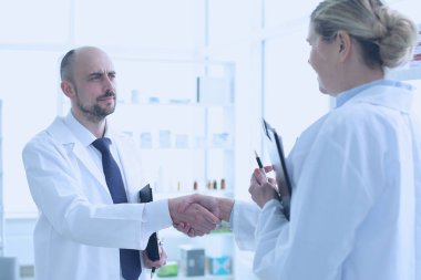 Eczacılar çalışıyor. Erkek ve kadın el sıkışıyor.