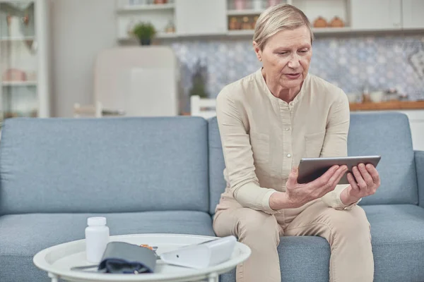 Senior woman using digital tablet at home. The use of technology by the elderly. — Stock Photo, Image