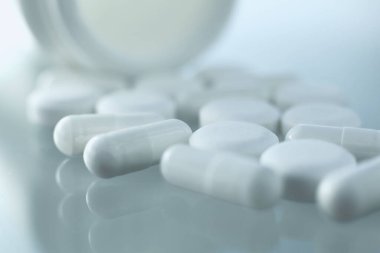 Cam bir masada, yanında tıbbi haplar olan plastik bir şişe yatar.