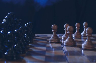 Satranç bir masa oyunudur. Karanlık bir arkaplanda satranç taşları