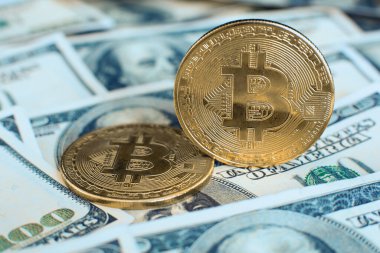 Altın bitcoin kripto para kendi ucunda duruyor, ikincisi yüz dolarlık banknotların üzerinde.