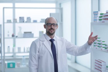 Eczacı çalışıyor. Eczanede özel sağlık üniforması giyen bir adam var..