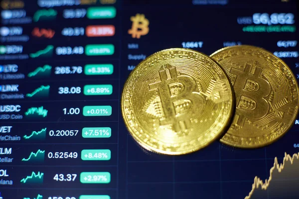 Dos monedas de oro bitcoin se encuentran en la pantalla de la tableta, que muestra indicadores de cambios en las tasas de criptomoneda — Foto de Stock