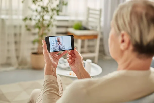 Sick woman during a video call with a doctor. Side view of patient talking during conference call with his doctor while at home during quarantine