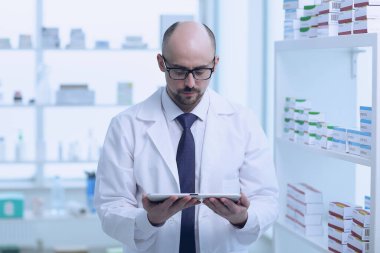 Eczacı çalışıyor. Eczanede özel üniformalı bir adam var..