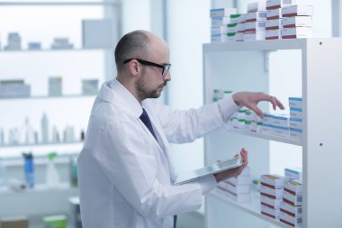 Eczacı çalışıyor. Eczanede özel üniformalı bir adam var..