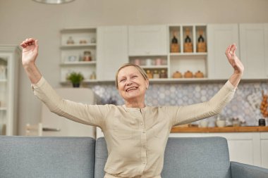 Yaşlı kadın kolları açık bir şekilde evde olmanın mutluluğunu yaşıyor. Mutlu emekliler konsepti
