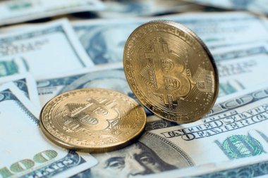 Altın bitcoin kripto para kendi ucunda duruyor, ikincisi yüz dolarlık banknotların üzerinde.