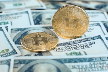 Altın bitcoin kripto para kendi ucunda duruyor, ikincisi yüz dolarlık banknotların üzerinde.