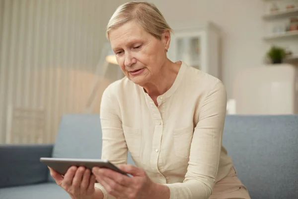 Evde dijital tablet kullanan yaşlı bir kadın. Yaşlılar tarafından teknoloji kullanımı..