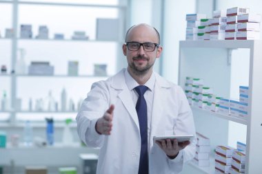 Eczacı çalışıyor. Eczanede özel üniformalı bir adam var..