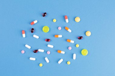 Mavi arka planda çeşitli şekillerde çok renkli haplar.