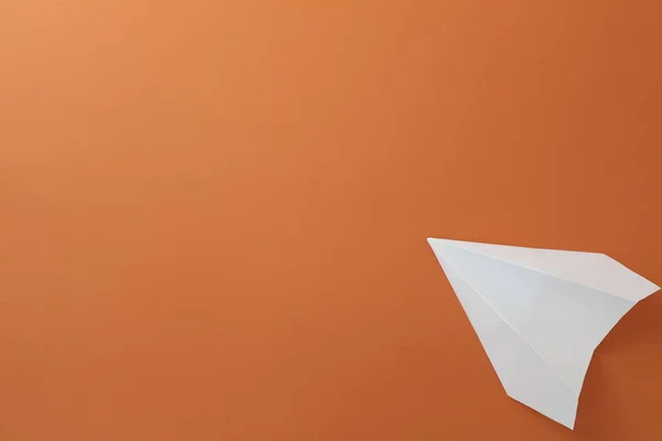 Paper white plane on orange background. Close-up