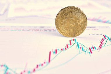 Altın bitcoin kripto para kendi ucunda duruyor. Kripto para birimindeki değişimlerin grafiği ofisteki ahşap bir masada yatıyor.
