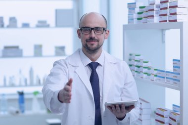 Eczacı çalışıyor. Eczanede özel üniformalı bir adam var..