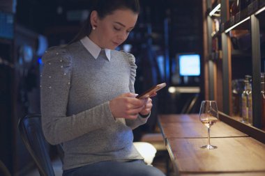Kız masada oturuyor ve bir kafede şarap içiyor. Çalışma gününden sonra dinlenme kavramı.