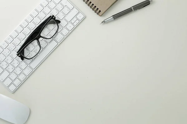 Glasses pen mouse keyboard and notepad on white background