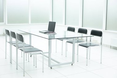 Geniş ofis alanındaki cam masadaki dizüstü bilgisayar.