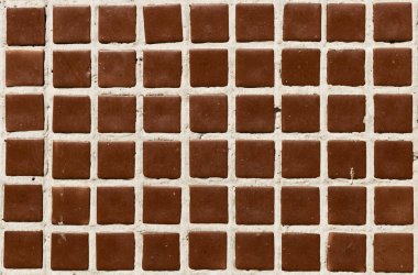 old concrete wall of a house, made of brown mosaic square elements, like chocolate or waffle