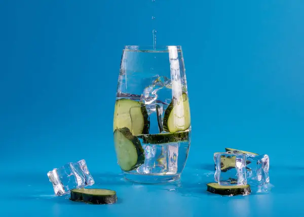 Інший Експеримент Склянці Шматочках Огірка Освіжаючому Льоду Фон Яскраво Блакитний — стокове фото