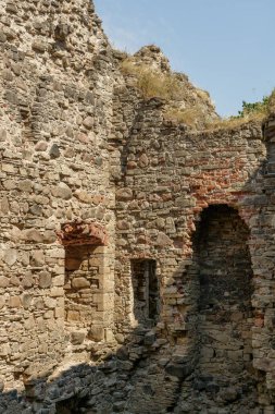 Binlerce yıllık şato harabeleri yazın, gün ışığında. Orta Çağ 'dan kalma pencere ve kapıların kalıntıları. Kral ve kraliçelerin dünyaya hükmettiği zamandan. Arka planda mavi gökyüzü. Harabelerde otlar büyür..
