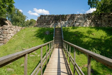 Merdiveni olan eski ahşap bir köprü. Tepedeki bilinmeyene çıkıyorlar. Çok sıcak bir yaz. Her yerde yeşil bir çim var, ama uzakta mavi bir gökyüzü, beyaz bulutlar ve merdivenlerin başında taş bir duvar var..