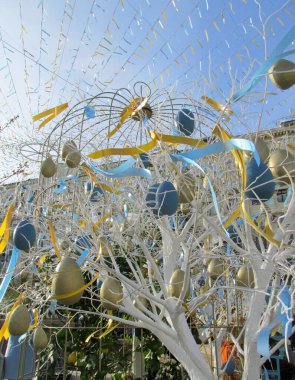 Renkli Paskalya yumurtaları mavi bahar gökyüzüne karşı bir ağaçta asılı duruyor. Bahar tatilleri için şehrin sokak dekorasyonunun kutlaması. Mutlu Paskalyalar. Moskova
