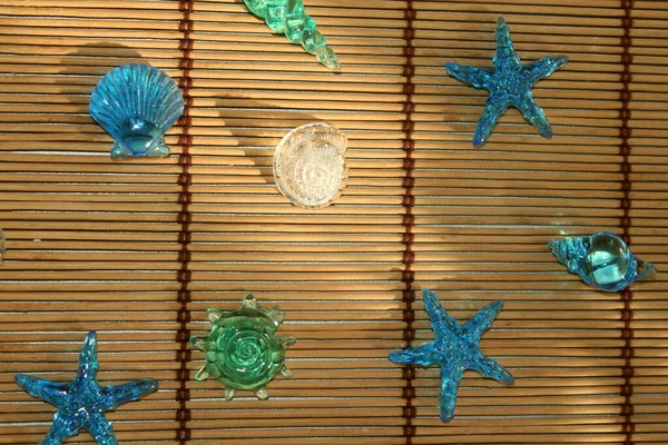 colorful glass shells and starfish on a background of bamboo sticks. top view