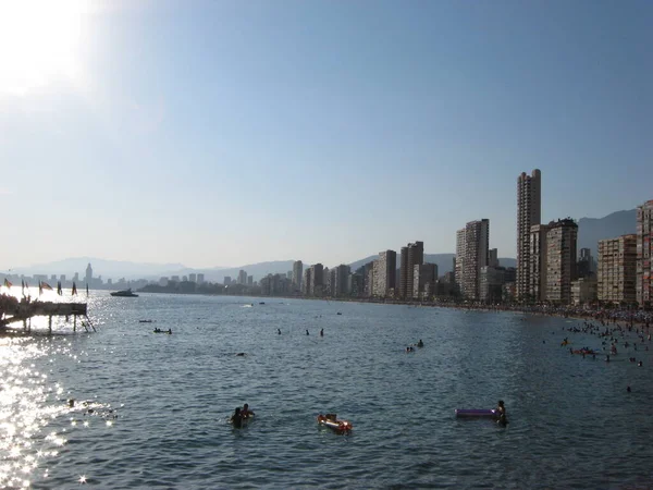İnsanlar denizde yüzer ve sahilde dinlenir. Costa Blanca 'da güneşli bir gün. Benidorm, İspanya