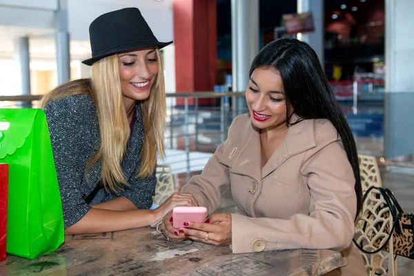 Young friends sitting in a coffee shop, sharing their shopping day on social media